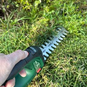 Mit dem langen Aufsatz der Bosch AdvancedShear 18V-10 wird Gras geschnitten.