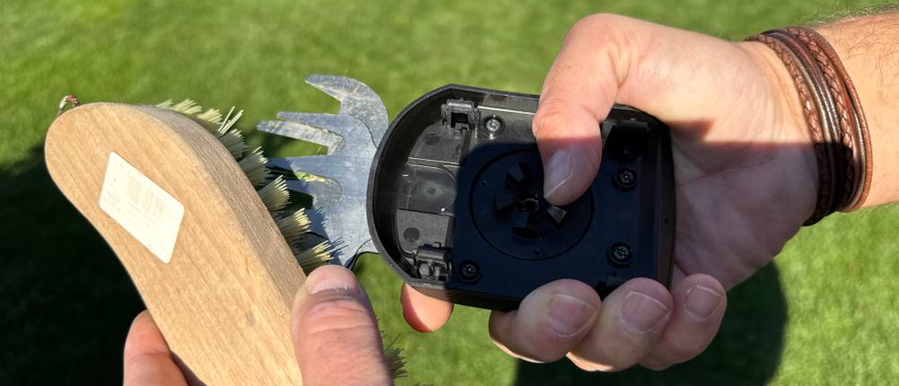 Eine Hand reinigt das Messer der Bosch AdvancedShear 18V-10 mit einer Bürste.