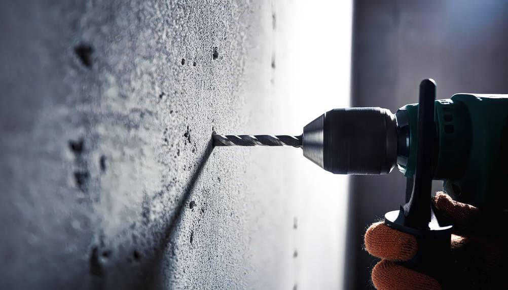 Bosch-Akku-Bohrhammer im Test: Eine Nahaufnahme eines Bohrhammers der in einer Betonwand ein Loch bohrt.