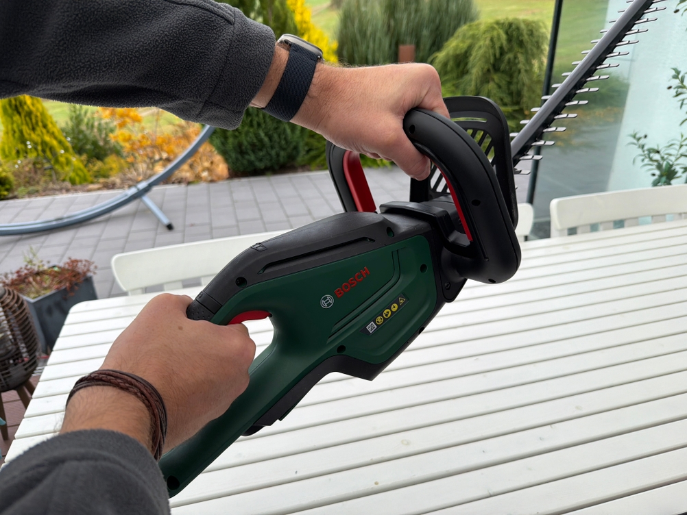 Eine Hand hält die Bosch-Akku-Heckenschere ‎0600849K01 fest