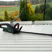 Die Bosch-Akku-Heckenschere ‎0600849K01 liegt auf einem Holztisch