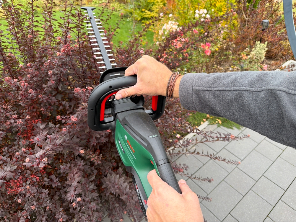 Ein Strauch wird mit der Bosch-Akku-Heckenschere ‎0600849K01 geschnitten