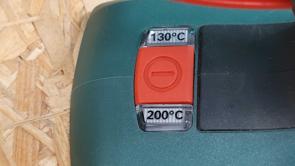 Temperaturschalter einer Heißklebepistole mit zwei Stufen auf einer Holzunterlage