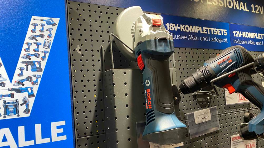 Im Test: Ein Bosch-Akku-Winkelschleifer hängt an einer Metallwand neben anderen Produkten.
