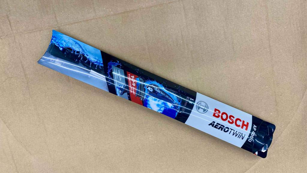 Scheibenwischer-Test: eine blau-weiße Bosch AeroTwin AP 400 U Verpackung auf beigefarbenem Karton.
