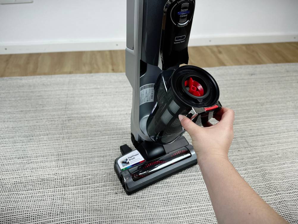 Eine Person entnimmt den Staubbehälter des Bosch Athlet Ultimate ProSilence BBH7PET zur Reinigung.