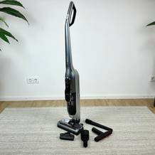 Der Bosch Athlet Ultimate ProSilence BBH7PET mit Ladestation und verschiedenen Düsen, aufgestellt in einem Wohnraum.
