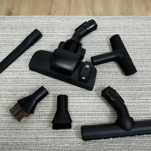 Das Bild zeigt das komplette Zubehör des Bosch BGL8XALL Staubsaugers auf einem Teppich. Zu sehen sind verschiedene Düsenaufsätze rund um die Bodendüse.