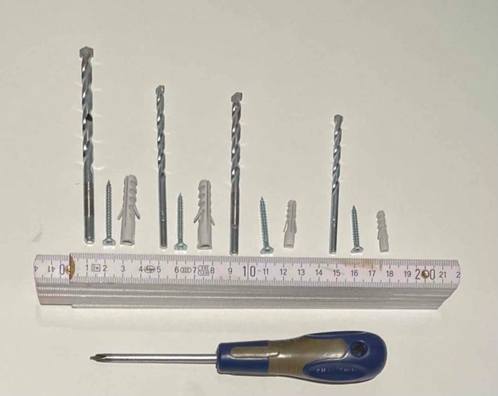 Dübel, Schrauben, Schraubenzieher und Metermaß liegen neben einem Bosch-Bohrer-Set im Test.