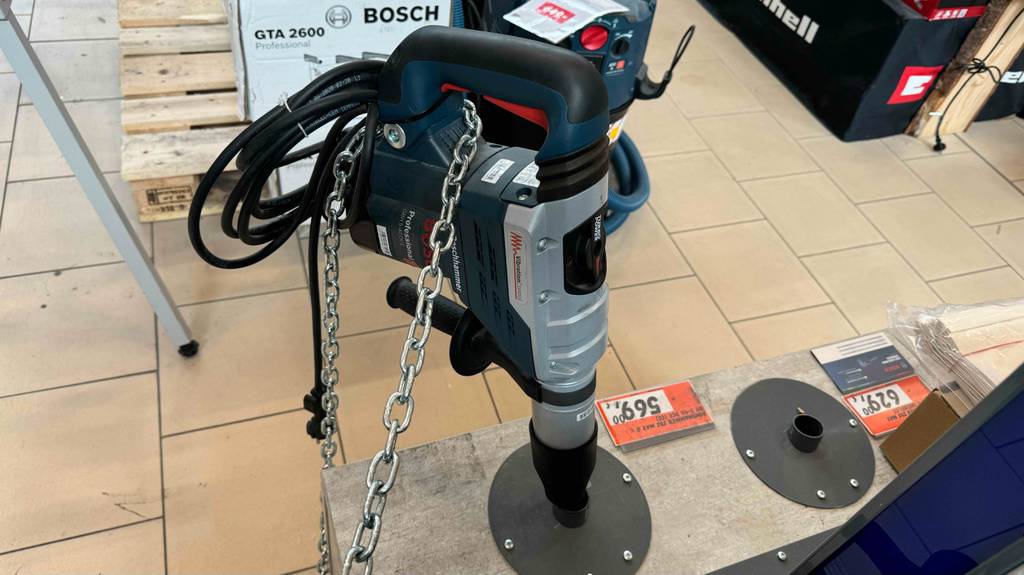 Gesamtansicht eines getesteten SDS-Max-Bohrhammers von Bosch, der gesichert in einem Baumarkt ausgestellt ist.
