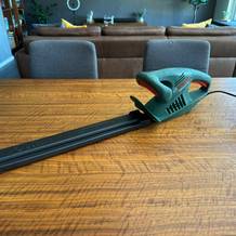 Die Bosch Easy Hedge Cut 45 liegt mit einem Schutz über dem Scherblatt auf einem Tisch.