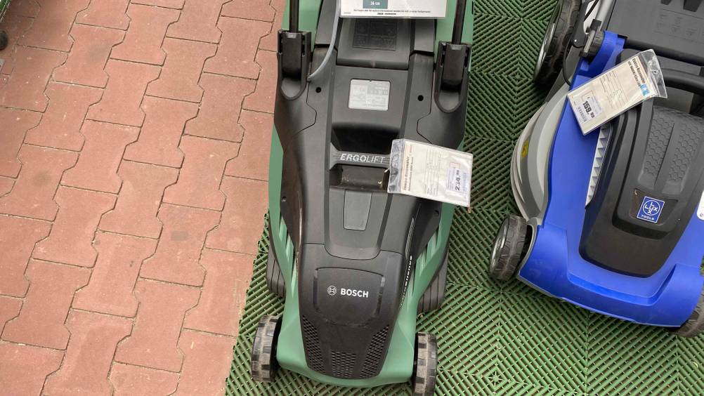 Auf dem Boden steht ein getesteter Elektro-Rasenmäher der Marke Bosch. 