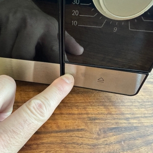 Eine Hand drückt den Knopf zum Öffnen der Tür der Bosch FFL020MS2 Serie 2