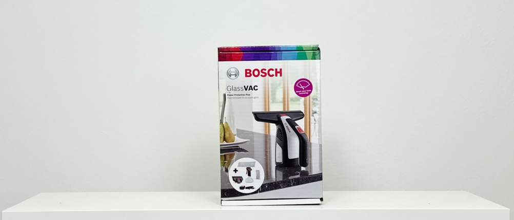 Die Bosch-GlassVAC-Produktverpackung steht mittig auf einem weißen Tisch. Auf der Verpackung sind Gerät und Zubehör abgebildet.