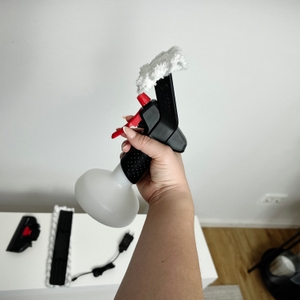 Die Bosch-GlassVAC-Sprühflasche wird senkrecht gehalten. Im Hintergrund liegt weiteres Zubehör auf einem weißen Tisch.