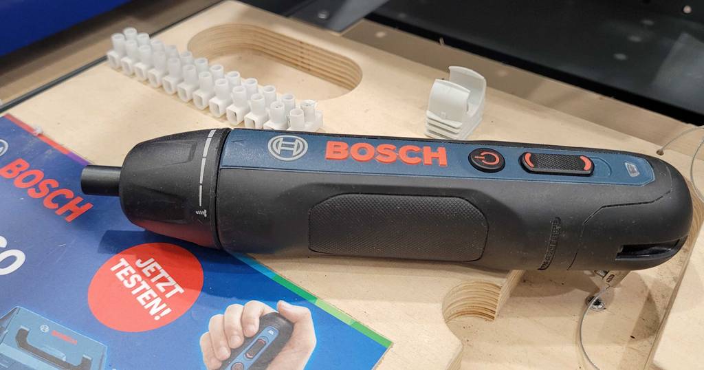Seitenansicht eines getesteten Bosch Professional Akkuschraubers, der auf einer Holzkiste vor Lüsterklemmen liegt.