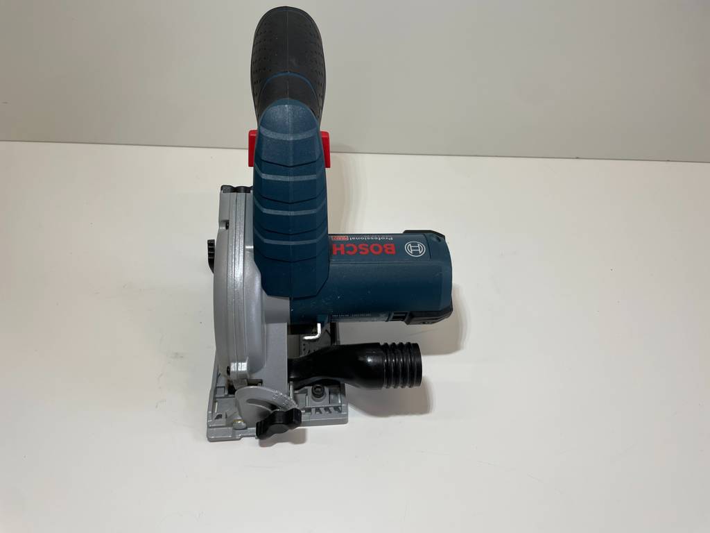 Eine Bosch-Handkreissäge im Test, mit Fokus auf den Staubsaugeranschluss, steht von oben gesehen auf einer weißen Oberfläche.