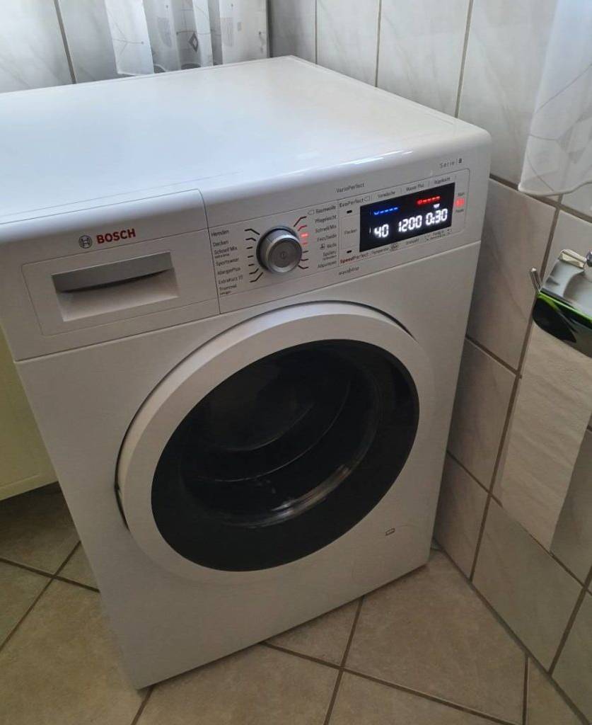 Wäschetrockner im Test steht mit eingeschaltetem Display in einem häuslichen Badezimmer.