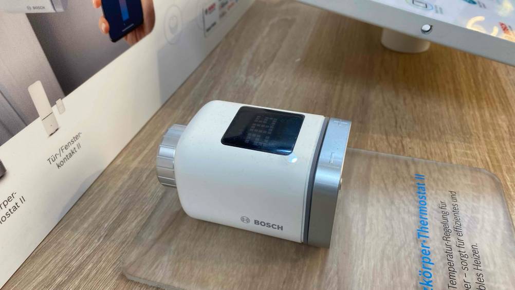 Getestet: Ein Heizkörperthermostat von der linken Seite auf einer transparenten Infotafel befestigt.