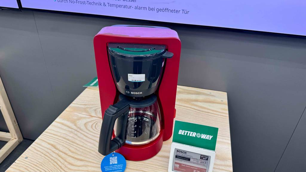 Frontansicht einer Bosch-Kaffeemaschine, die zum Testen mit Verkaufsschild auf einem hellen Tisch steht.