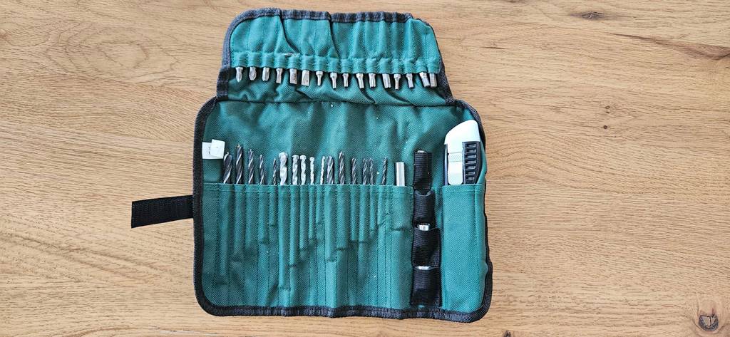 Zubehörset mit Bohrern und Bits eines getesteten Bosch Akkuschraubers liegt ausgebreitet auf einem Boden.