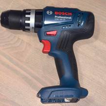 Seitliche Gesamtansicht des Bosch Professional GSB 18V-25 Akkuschlagbohrschraubers ohne Akku. Das Gerät liegt auf einem Holzuntergrund.