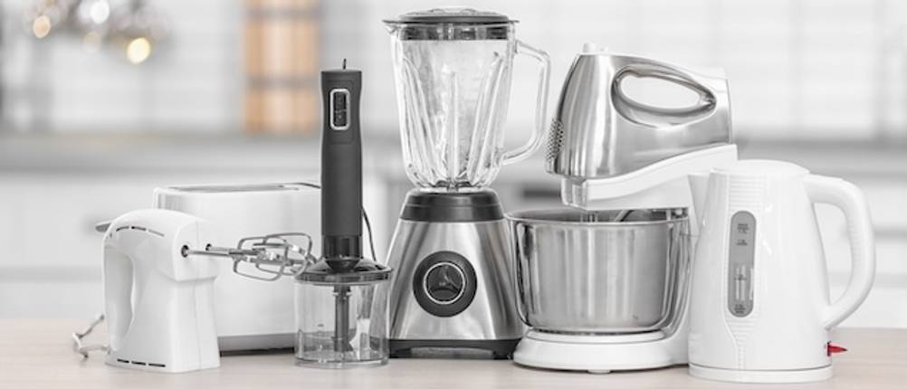 Küchengeräte im Test: Auf einer Arbeitsplatte befinden sich zahlreiche Küchengeräte wie Mixer, Smoothie-Maker, Stabmixer, Küchenmaschine und Rührgerät - alle in Schwarz, Weiß und Edelstahl.