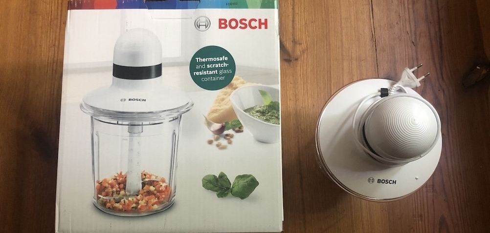 Bosch-Zwiebelschneider steht neben der Verpackung auf einem Tisch.