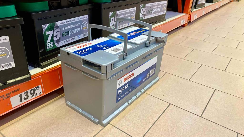 95-Ah-Autobatterien im Test: eine hellgraue Bosch-Autobatterie P0013 steht vor einem Verkaufsregal mit weiteren Autobatterien.