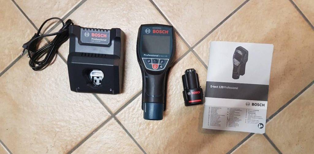 Sicht von oben auf eine Bosch Wärmebildkamera zwischen seiner Ladestation und der Bedienungsanleitung auf Fliesen.