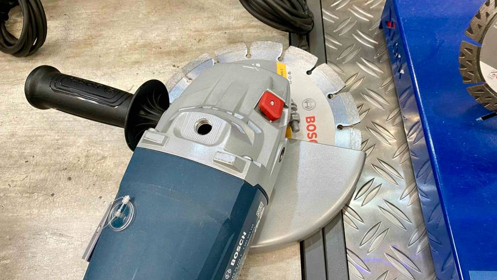 Nahaufnahme des Kopfes eines Winkelschleifer-230-mm im Test mit Schleifscheibe und Zusatzgriff.