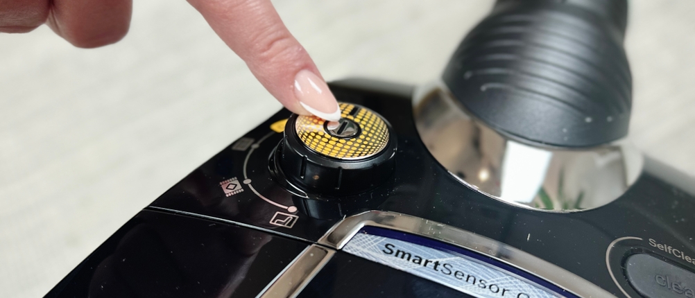 Das Bedienfeld des Bosch ProSilence Serie 8 BGS7MS64 ist aus der Nähe zu sehen. Eine Hand bedient den Drehregler zur Einstellung der Saugleistung.