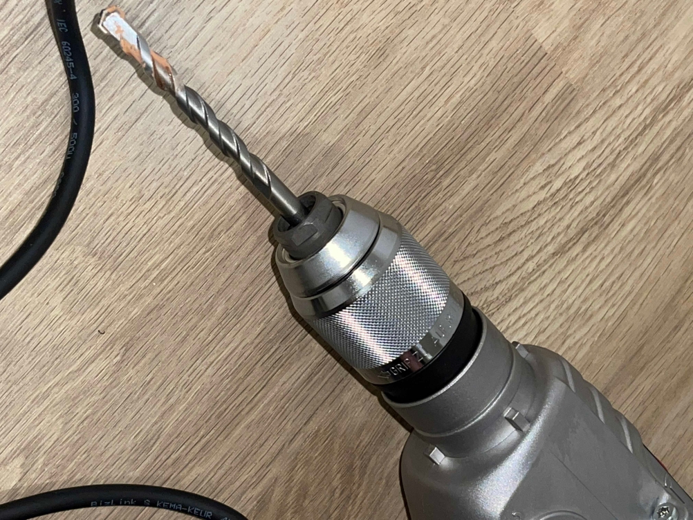 Nahaufnahme des Schnellspannbohrfutters der Bosch GSB 21-2 RCT mit eingesetztem Bohrer auf Holzuntergrund.