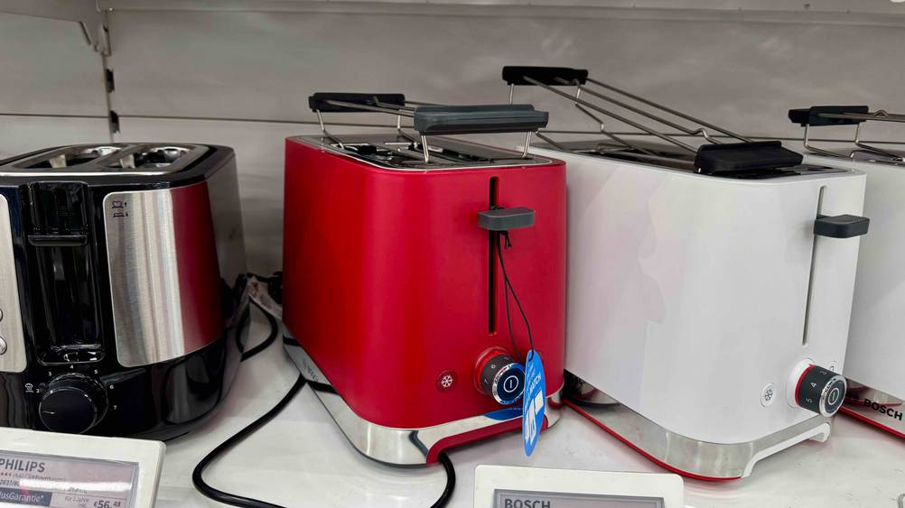 In einem Regal neben anderen Produkten steht ein Bosch-Toaster im Test seitlich.