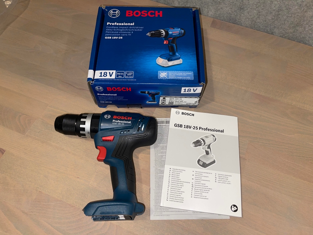 Unboxing der Bosch GSB 18V-25 Professional mit Box, Gerät und Bedienungsanleitung auf Holzboden.