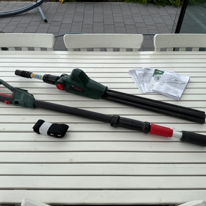 Der Lieferumfang der Bosch Universal HedgePole 18 liegt auf einem Tisch