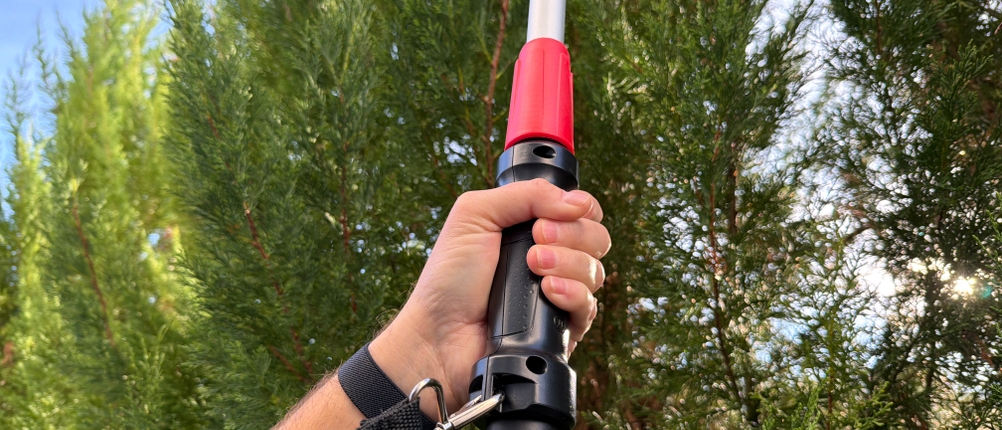 Eine Hand hält die Bosch Universal HedgePole 18 am vorderen Griff fest