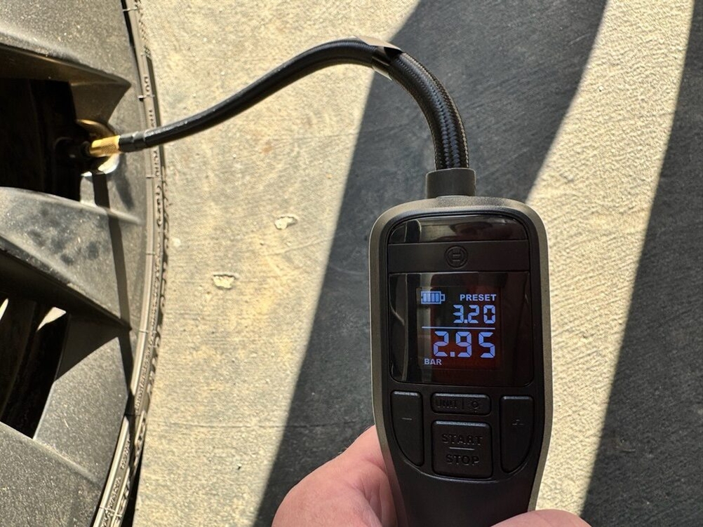 Das Display der Bosch UniversalPump zeigt 2,95 bar an, während ihr Schlauch am Ventil eines Autoreifens angeschlossen ist