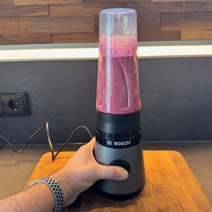 Der An-Knopf des gefüllten Smoothie-Makers wird gedrückt.