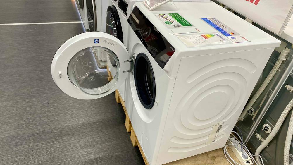 Eine Waschmaschine 10 kg im Test von schräg oben auf einem Sockel mit geöffneter Klappe.