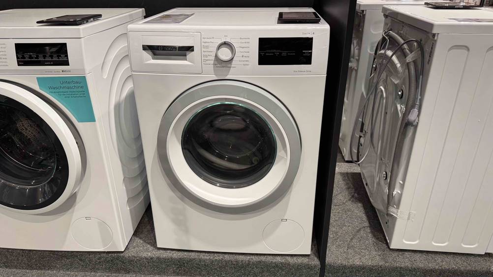 Eine getestete Bosch-Waschmaschine Serie 4 steht zwischen anderen Geräten in einer Verkaufsfläche.