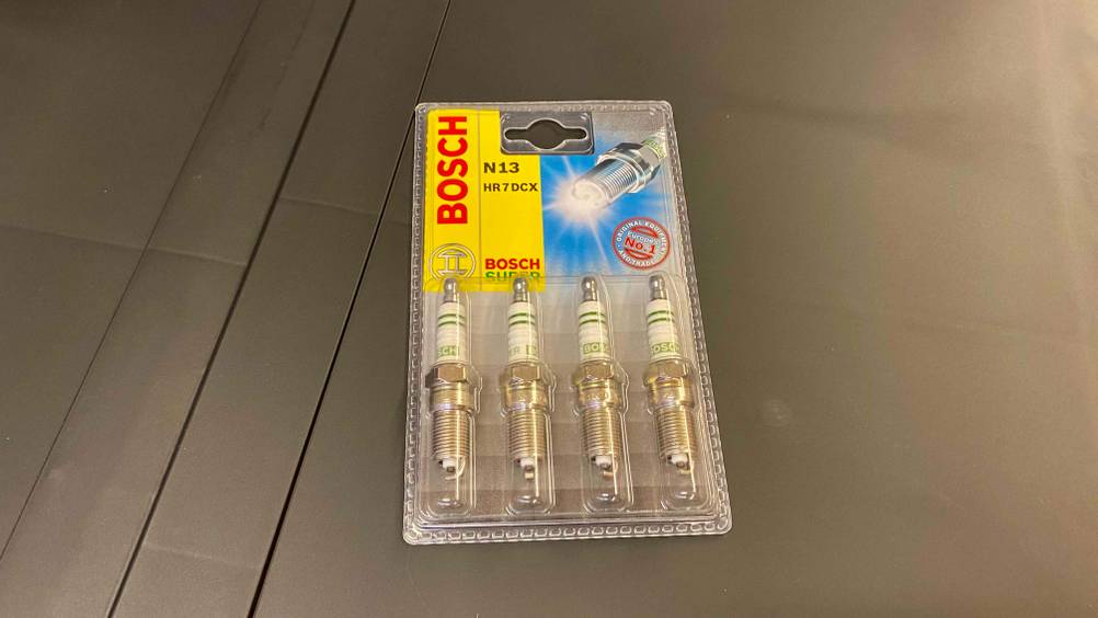 Im Test: Auf einer grauen Fläche liegt eine Packung mit vier Zündkerzen.
