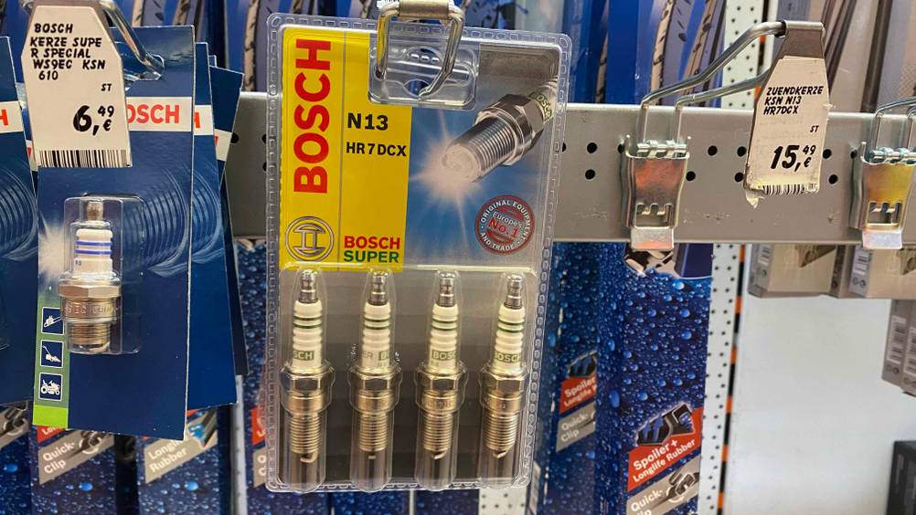 Eine Packung der getesteten Zündkerzen hängt in einem Verkaufsregal neben anderen Produkten.