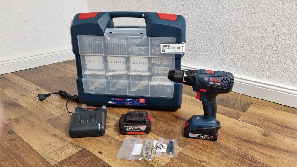 Schlagbohrschrauber-Set mit Bit, Akku, Schrauber und Koffer stehen auf dem Boden