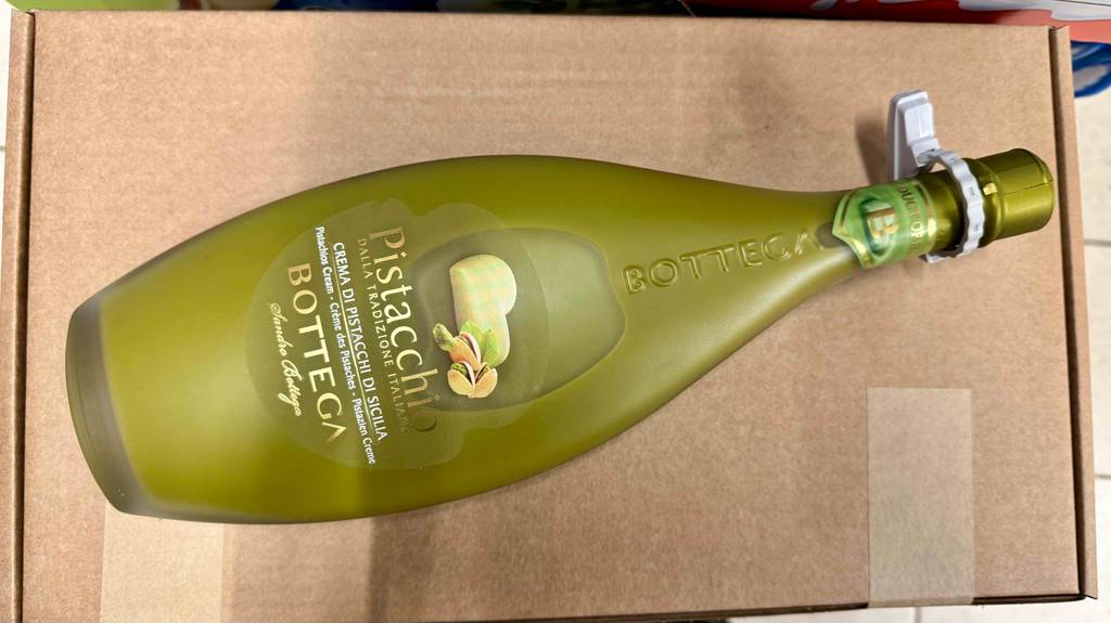 Pistazienlikör-Test: Eine bauchige Flasche mit Naturkorken liegt auf einem braunen Karton.