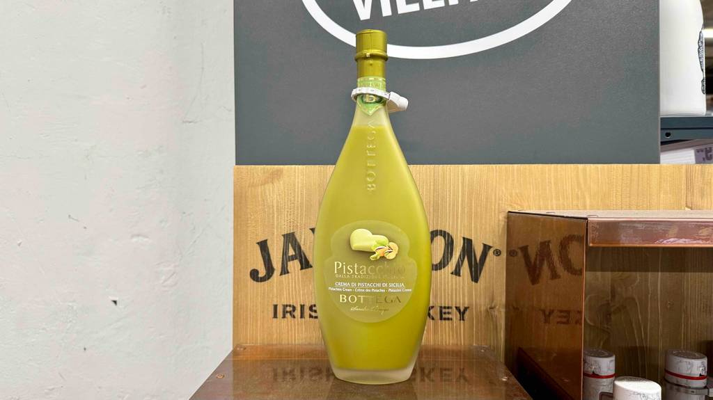 Pistazienlikör getestet: Eine bauchige Flasche mit Naturkorken steht auf einem Ausstellungsregal.