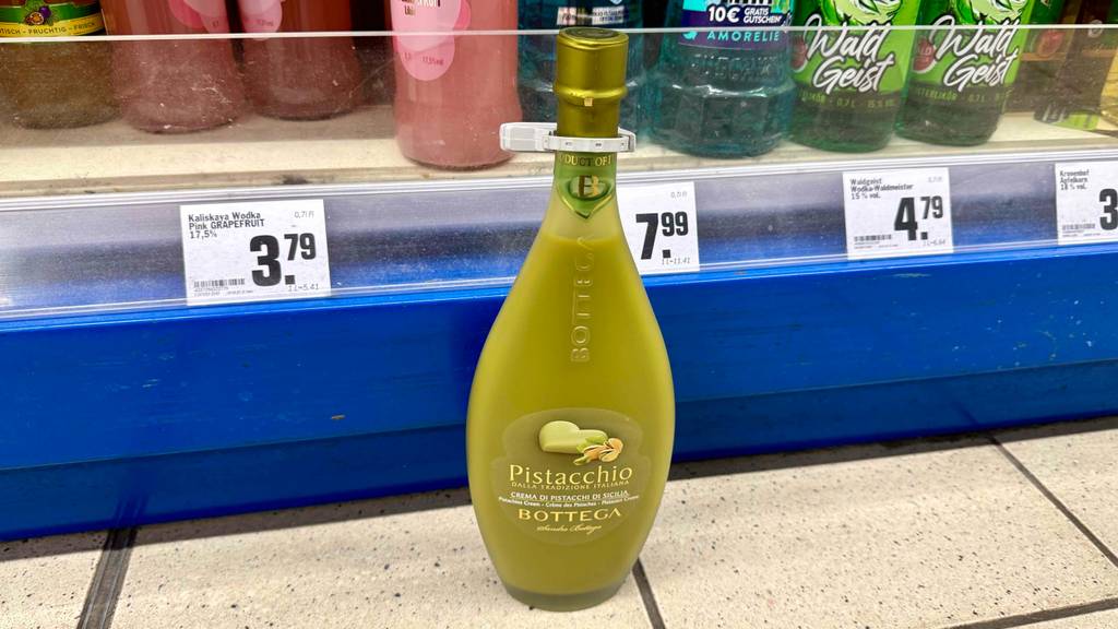 Pistazienlikör im Test: Eine bauchige Flasche mit Naturkorken steht vor einem Verkaufsregal.