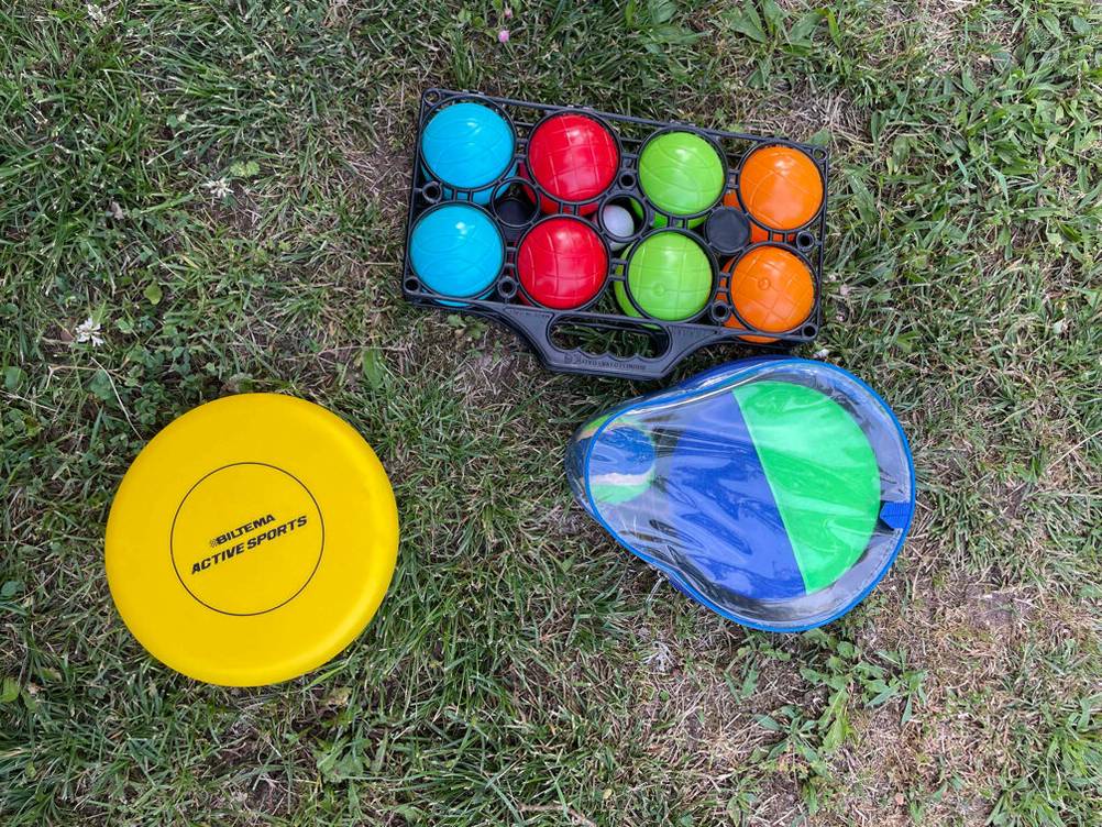 Boule getestet: Ein Set Boule neben einem anderen Ballspiel und einem Frisbee auf Gras.