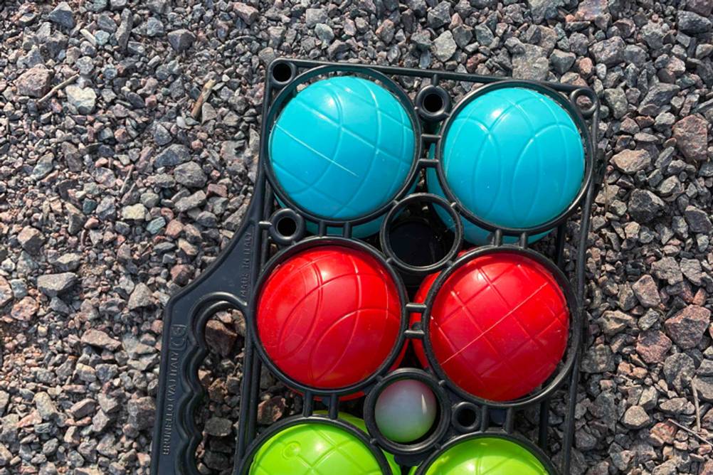 Nahaufnahme der getesteten Boule-Bälle im Tragenetz auf Kies.