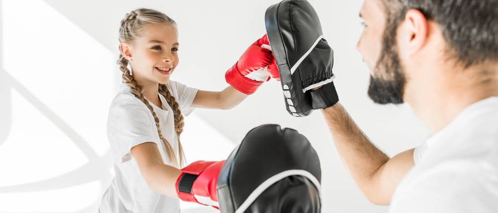Boxhandschuhe-Kinder-Test: Ein Mädchen übt gerade das Pratzen-Training.